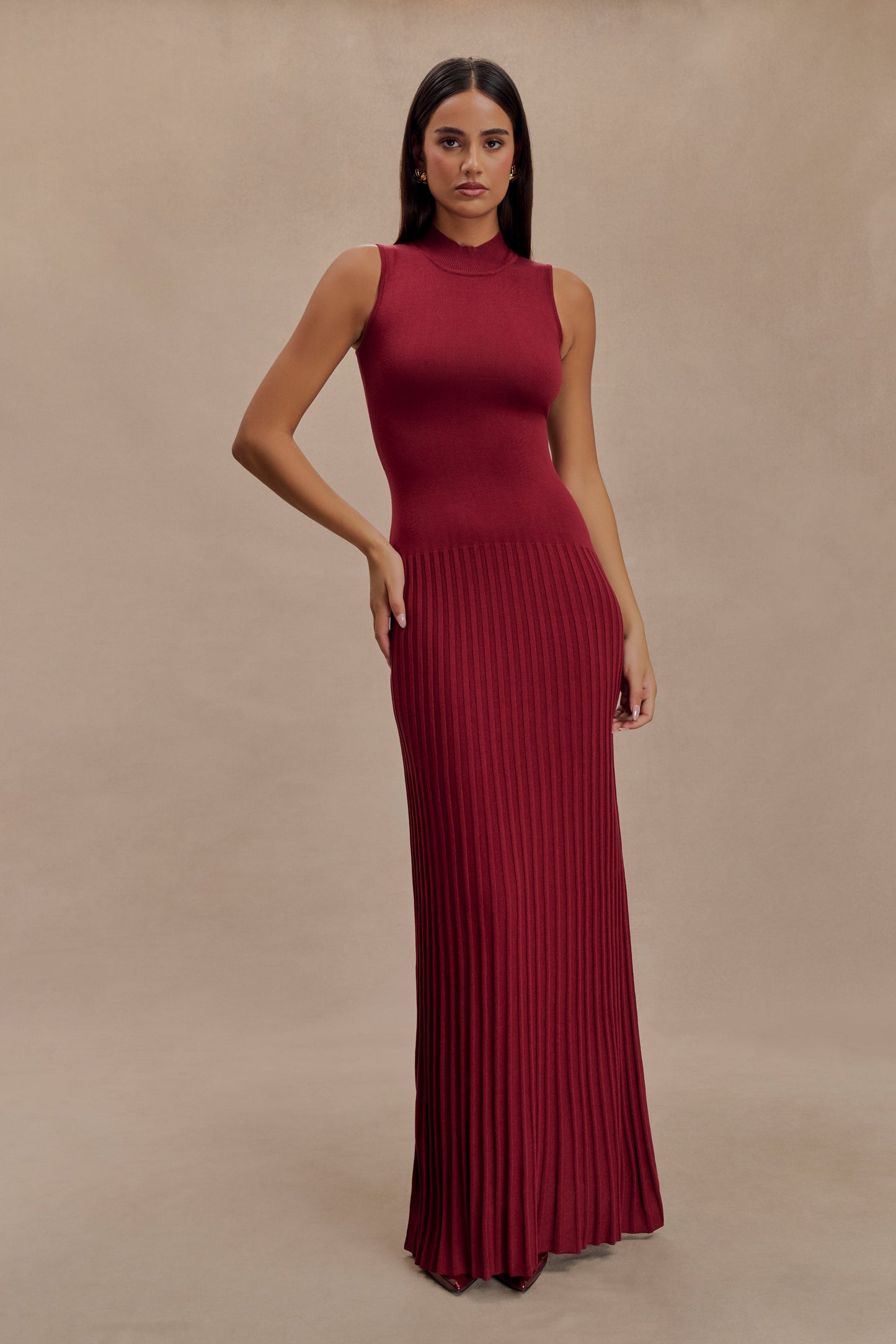 Vrouw draagt de Selena bordeauxrode plissé maxi jurk in een klassieke setting