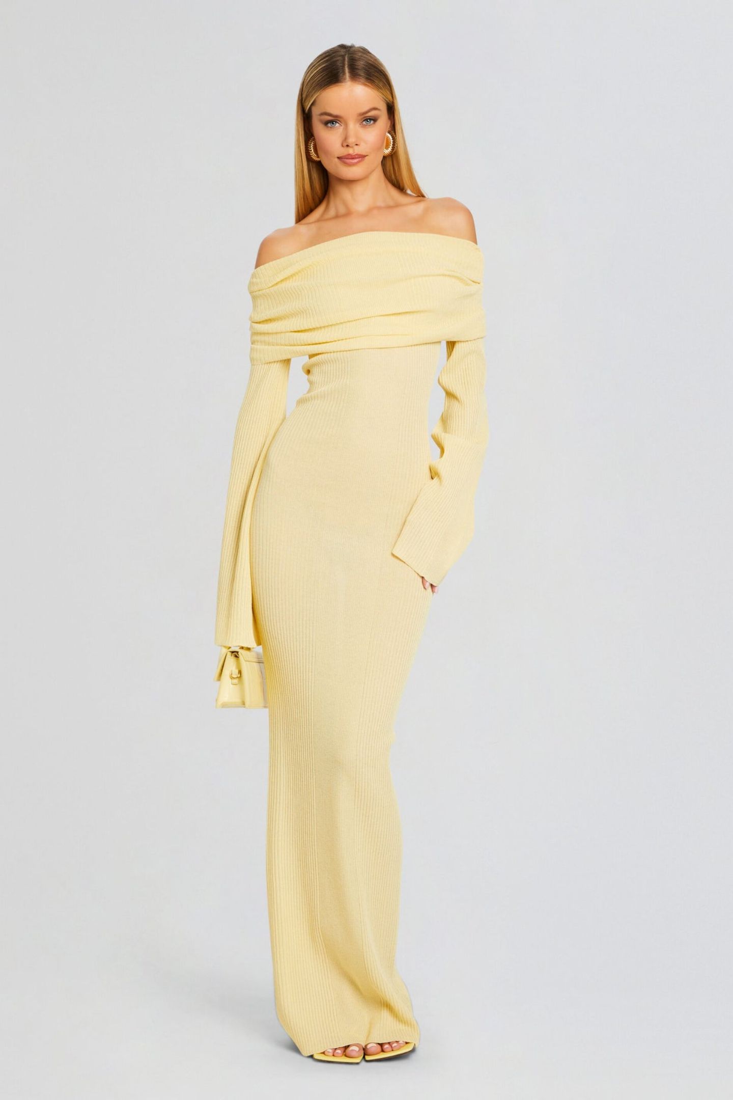 Vrouw draagt de Marina off-shoulder maxi jurk in lichtgele kleur met lange mouwen
