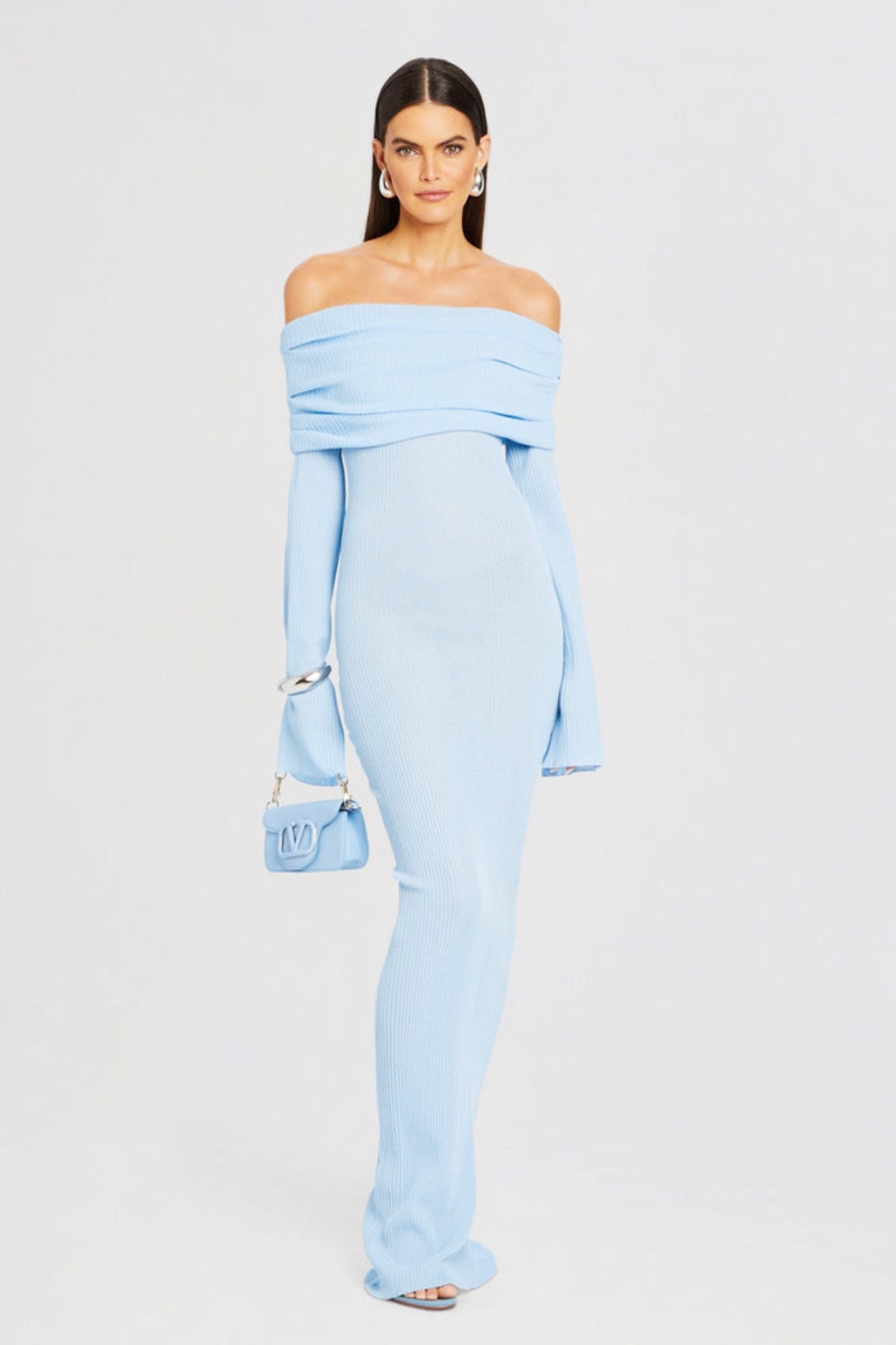 Vrouw draagt de Marina off-shoulder maxi jurk in blauwe kleur met lange mouwen