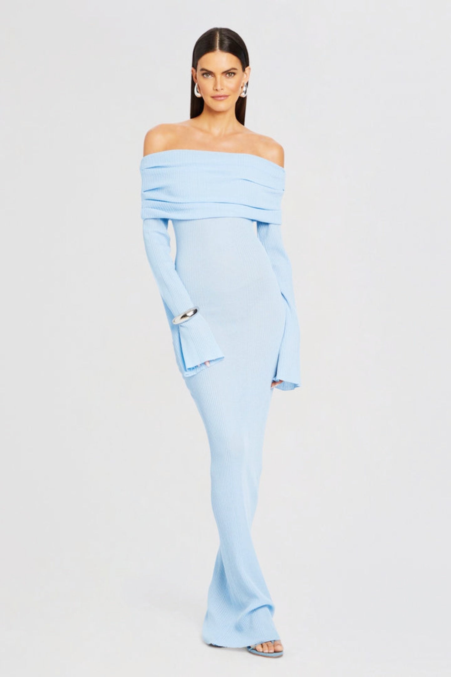 Vrouw draagt de Marina off-shoulder maxi jurk in blauwe kleur met lange mouwen