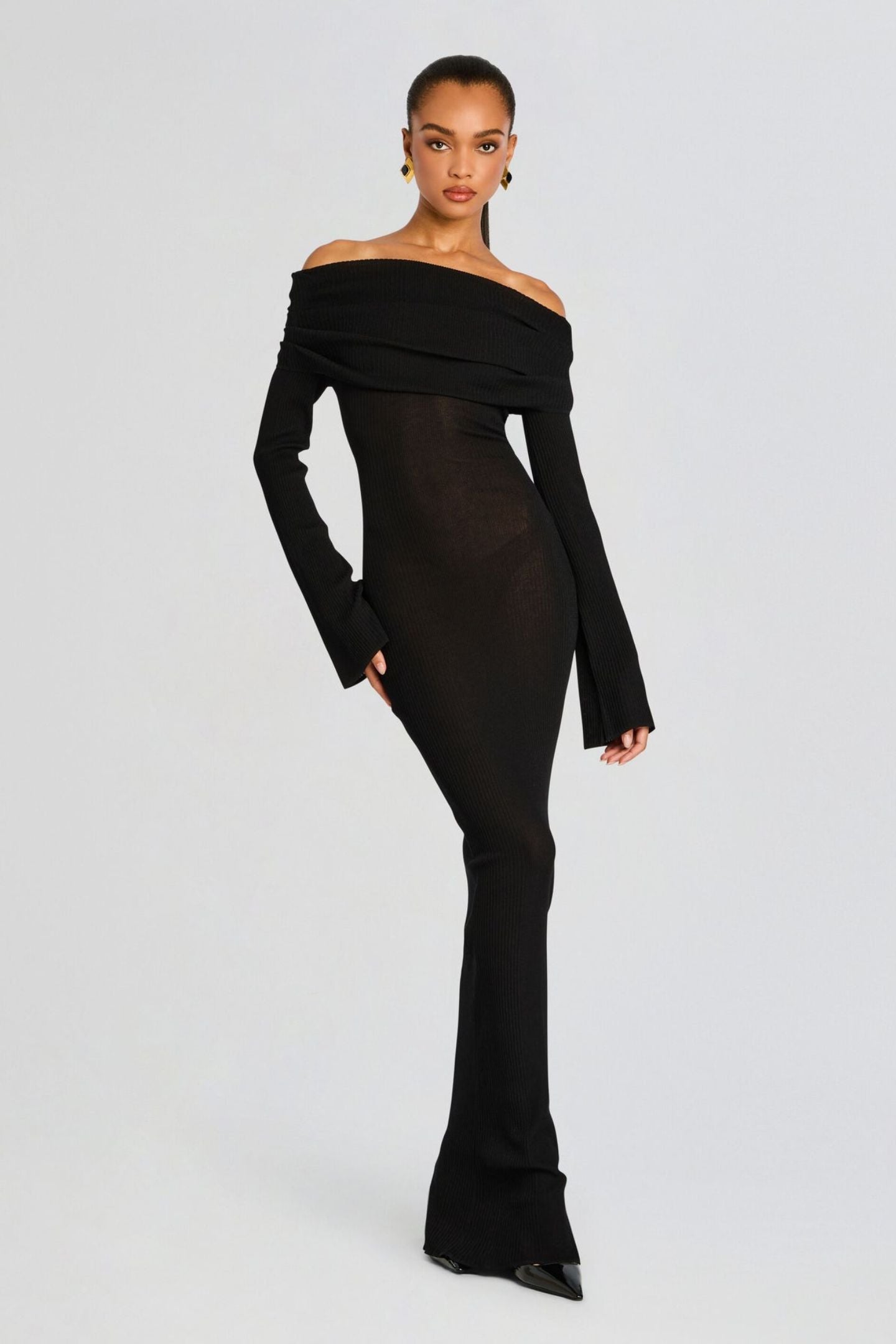 Vrouw draagt de Marina off-shoulder maxi jurk in zwarte kleur met lange mouwen