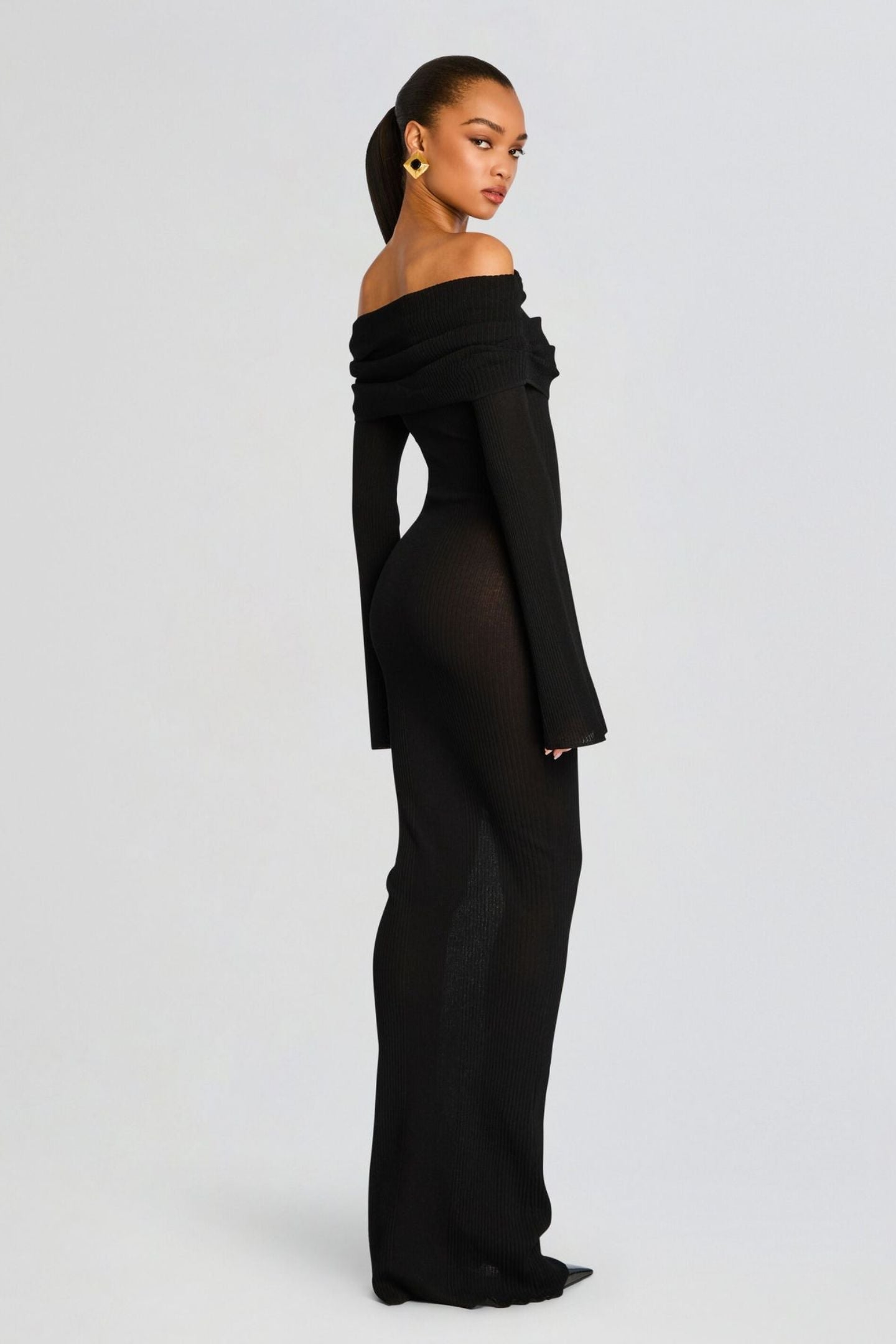 Vrouw draagt de Marina off-shoulder maxi jurk in zwarte kleur met lange mouwen