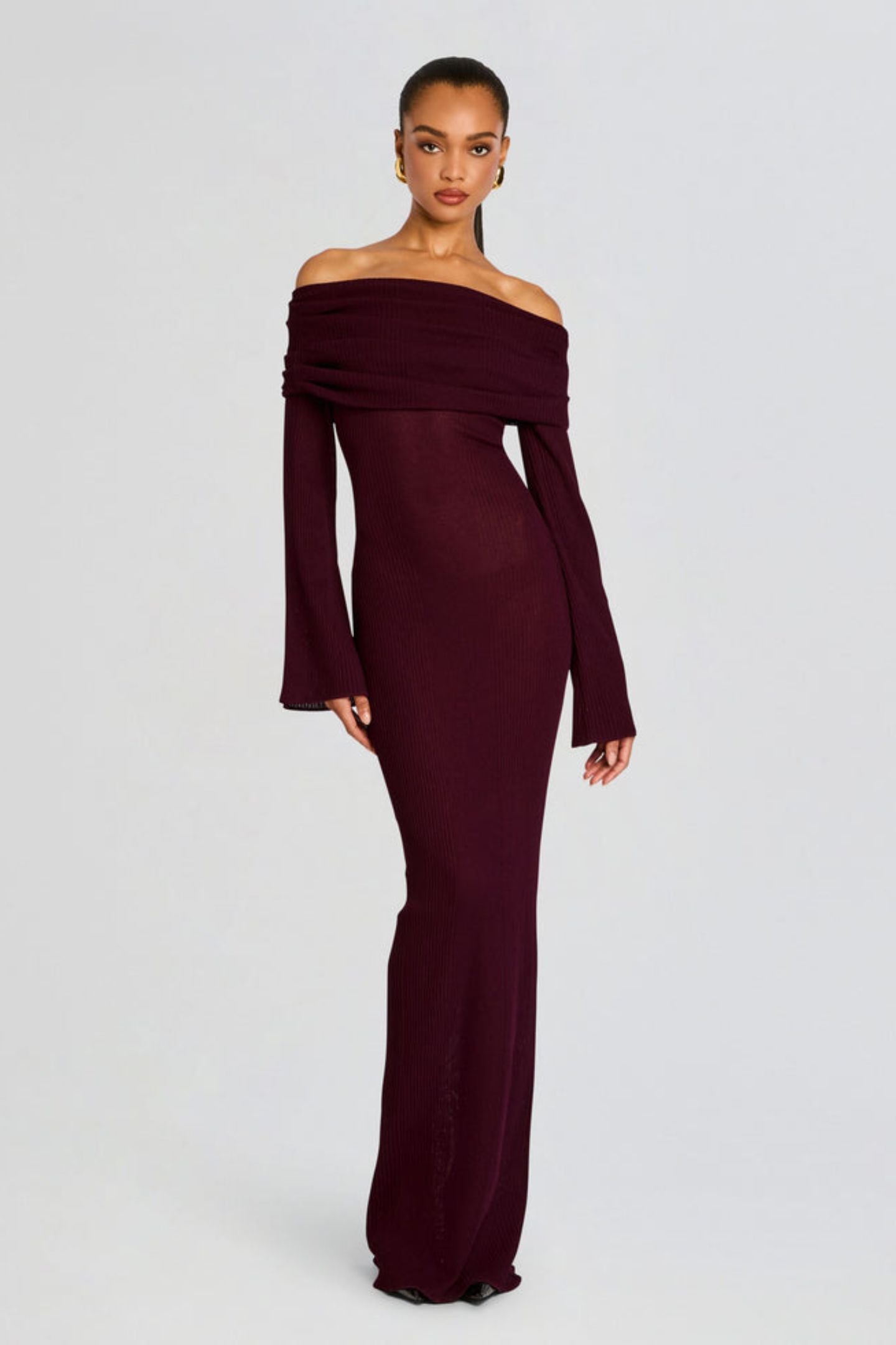 Vrouw draagt de Marina off-shoulder maxi jurk in rode kleur met lange mouwen
