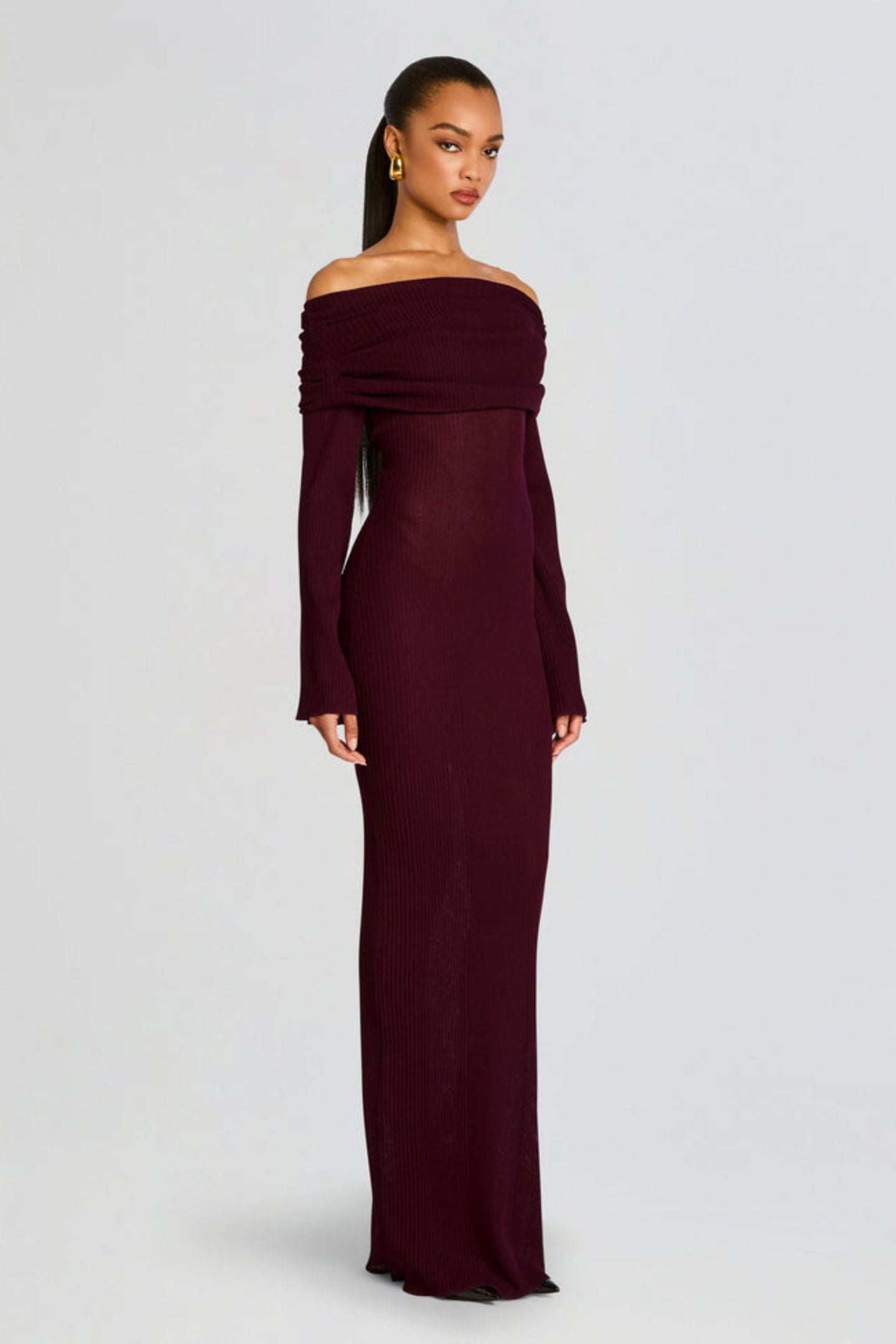 Vrouw draagt de Marina off-shoulder maxi jurk in rode kleur met lange mouwen