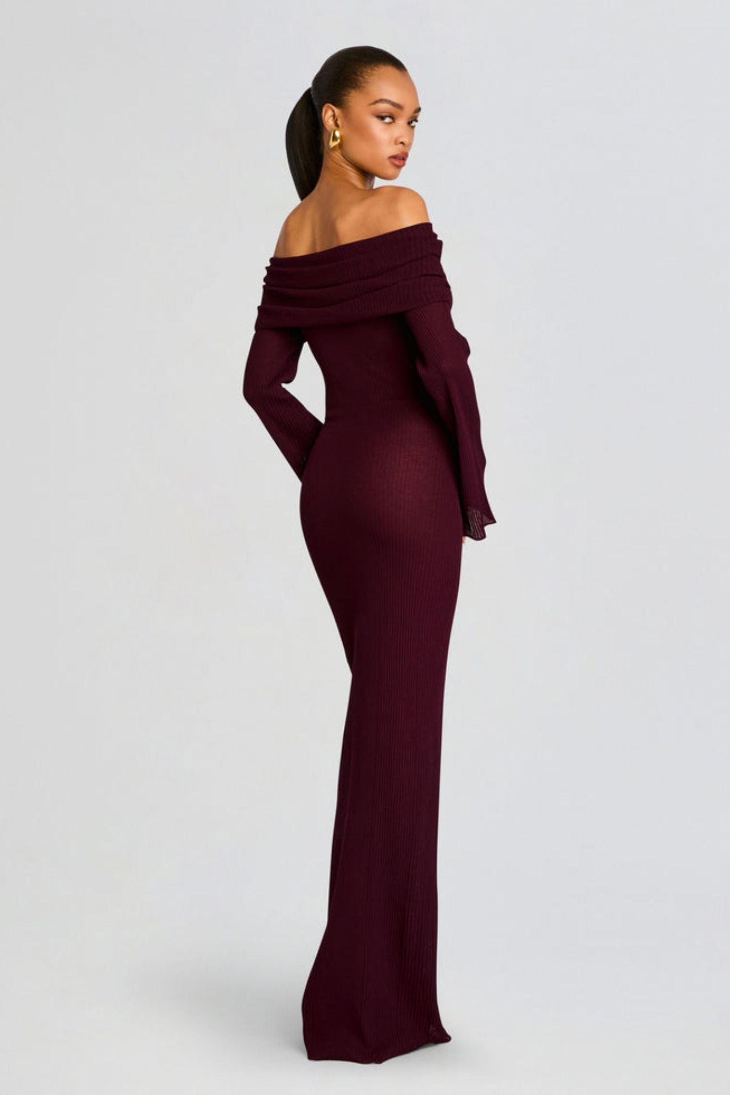 Vrouw draagt de Marina off-shoulder maxi jurk in rode kleur met lange mouwen