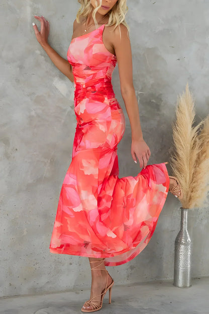 Vrouw draagt de Amara asymmetrische bloemenjurk met oranje  bloemenprint