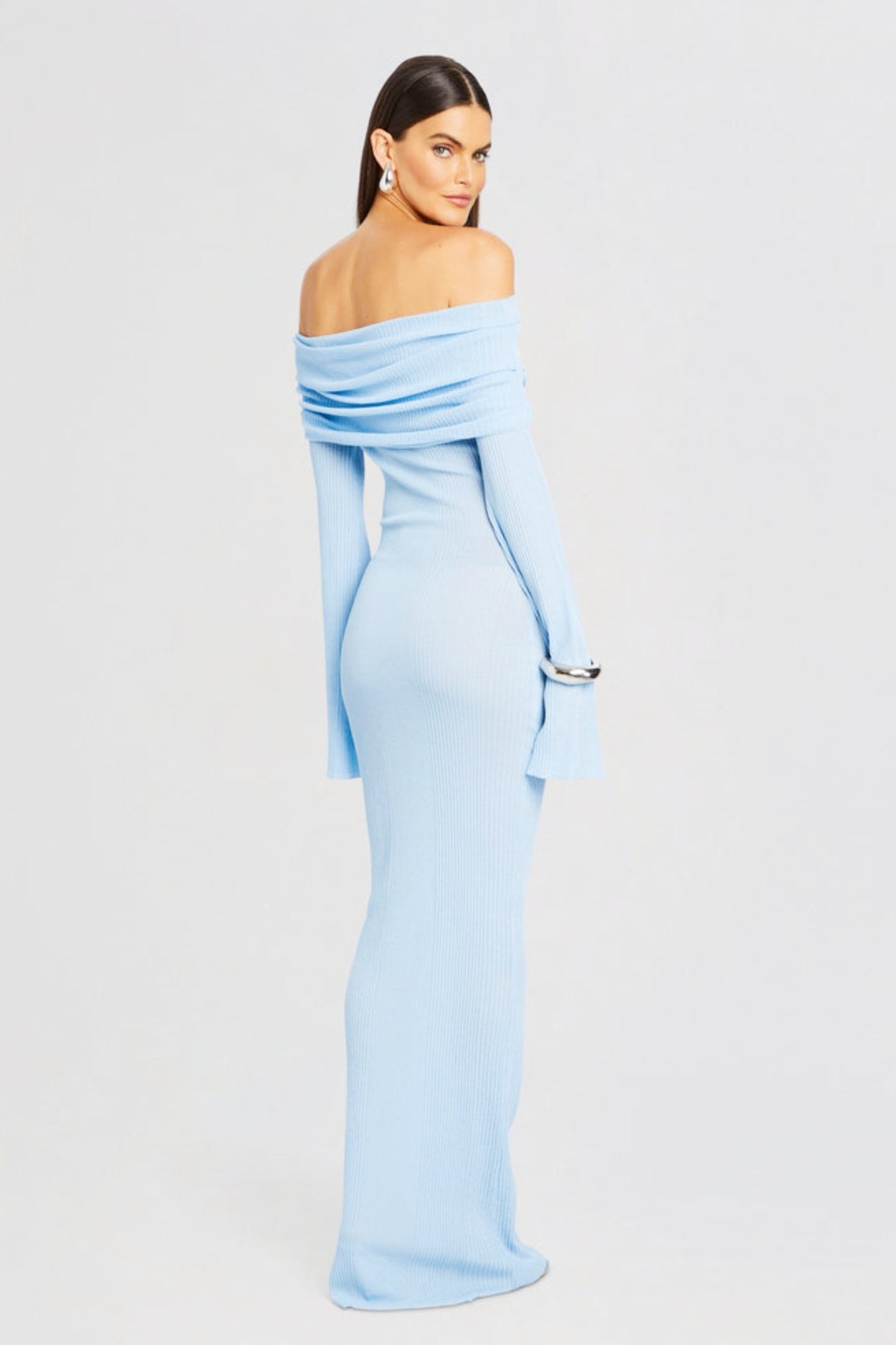Vrouw draagt de Marina off-shoulder maxi jurk in blauwe kleur met lange mouwen