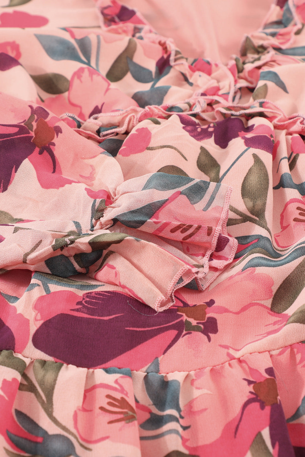 Close-up van bloemenprint maxi-jurk met V-hals en ruches, satijnachtige stof in crème met rode en groene accenten
