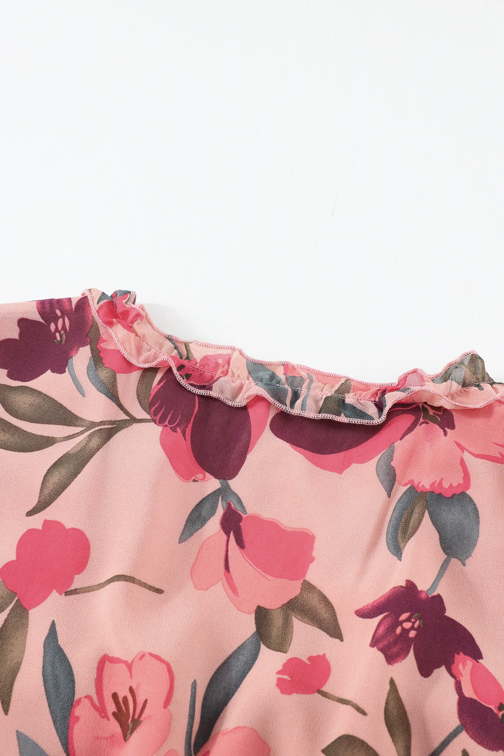 Close-up van bloemenprint maxi-jurk met V-hals en ruches, satijnachtige stof in crème met rode en groene accenten