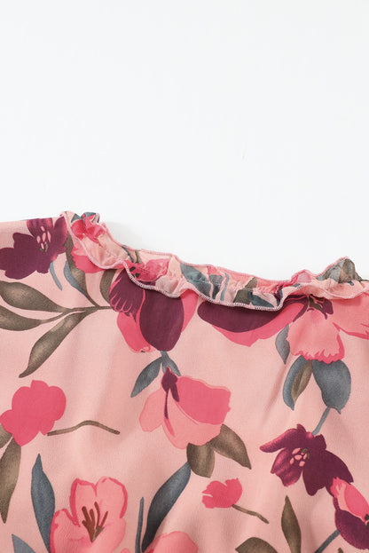 Close-up van bloemenprint maxi-jurk met V-hals en ruches, satijnachtige stof in crème met rode en groene accenten